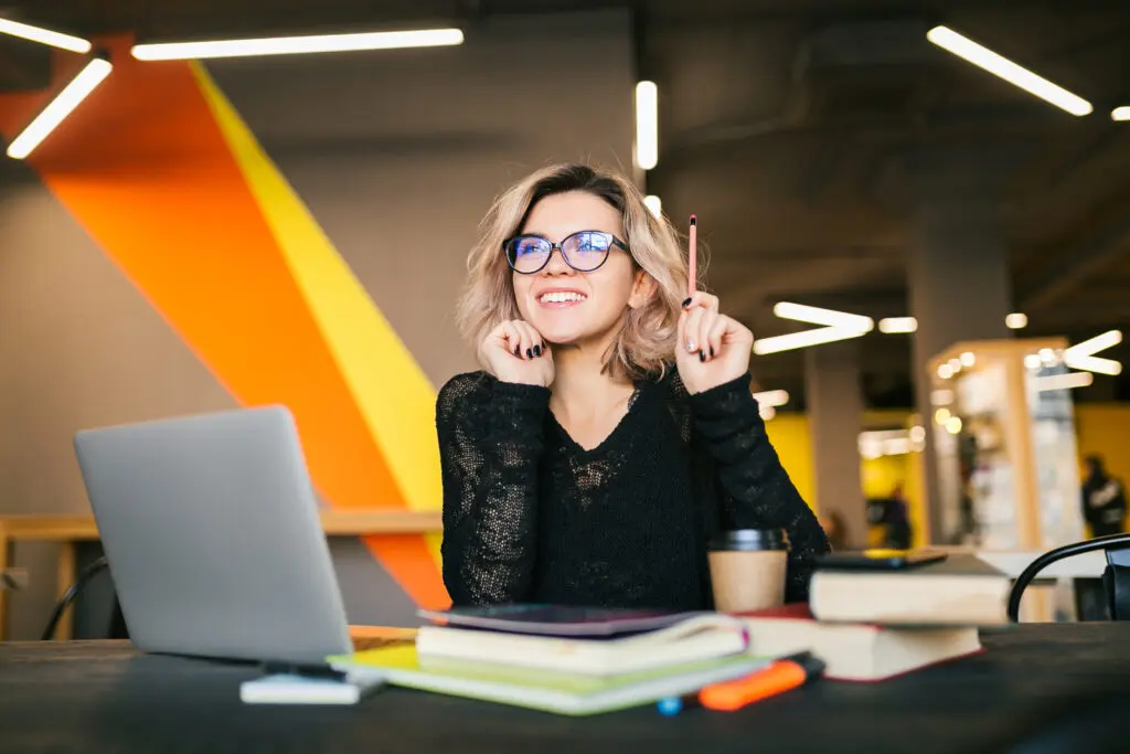 Software BPM para incrementar la productividad del equipo y dismución de errores humanos 2 retrato de joven mujer bonita sentada la mesa con camisa negra trabajando en un portatil en la oficina de trabajo conjunto Digital Ware
